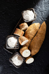 pile of cassava and cassava flour on dark background (Manihot esculenta)