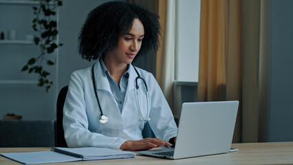 Fototapeta na wymiar African woman doctor physician student of medical university intern psychotherapist use laptop female therapist nurse consulting patient distantly in online chat type recipe for patient on computer 