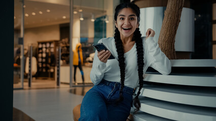 Female winner indian arabian ethnic girl businesswoman student use modern smartphone shopping online win internet discounts on mobile phone achieve business profit young pretty woman celebrate success