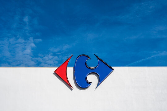 Anglet, France - 26 avril 2023: Logo du groupe Carrefour sur un fond de mur blanc et de ciel bleu