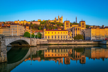 Obraz premium Lyon city skyline, buildings, and landmark architectures at sunrise with water reflections in the Saone River in France