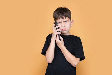 A tired sad young boy of 8 years old is talking on phone and complains to his mother that he has a...