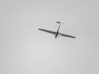 Glider with propeller flying in gray sky