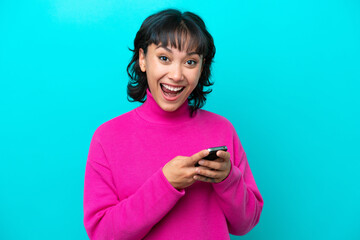 Young Argentinian woman isolated on blue background surprised and sending a message