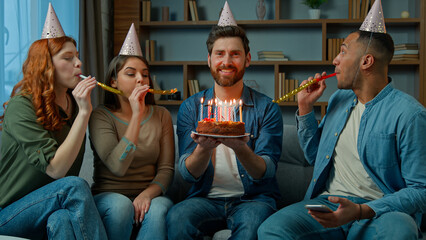 Birthday man happy adult bearded guy hold festive cake burning candles diverse group friends...