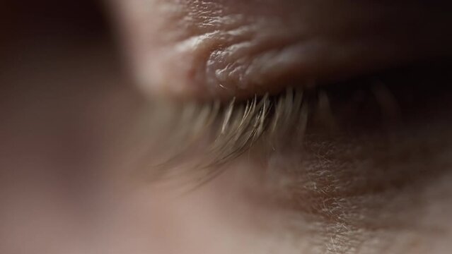 Profile side view of a closed human eye with details on eyelashes. Slow motion. Shallow depth of field. 