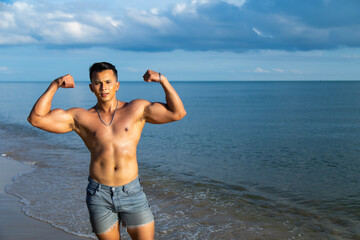 Handsome young muscular Asian man on summer beach