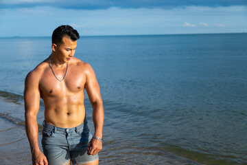 Fototapeta na wymiar Handsome young muscular Asian man on summer beach
