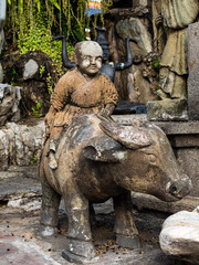 Closeup of a statue of a buddhist monk riding on a bull at the Wat Pho Temple in Bangkok, Thailand.