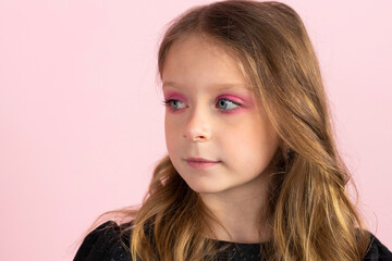Portrait of a Charming little girl in black stylish summer dress and slight pink makeup. Isolated on pink background.