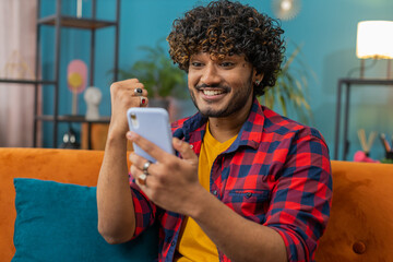 Happy indian man use mobile smartphone typing browsing say Wow yes found out great big win good...