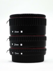 closeup of a black camera lens extension adapter tube set for macro photography isolated in a white...