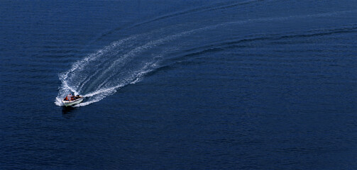 Naklejka premium A speedboat rushes at great speed through the water, leaving a foamy trail. View from above. Space for copying.
