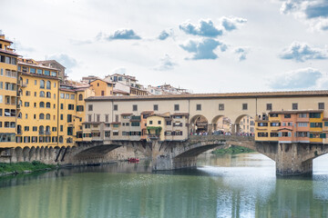 Fototapeta na wymiar Ponte Vecchio Bridge, a medieval stone closed-spandrel segmental arch bridge over the Arno River with shops along it. In Florence, Italy