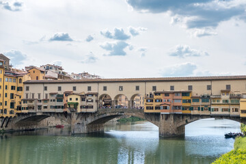 Fototapeta na wymiar Ponte Vecchio Bridge, a medieval stone closed-spandrel segmental arch bridge over the Arno River with shops along it. In Florence, Italy