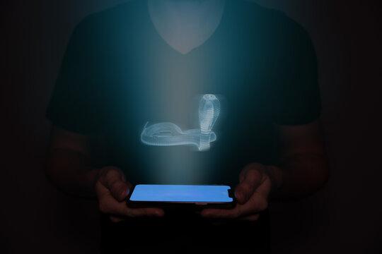 A young man from the future holds a smartphone onto which a snake is projected. Future technology.