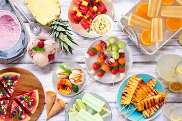 Refreshing summer food table scene. Assortment of grilled fruits, ice cream and ice pops. Top down...