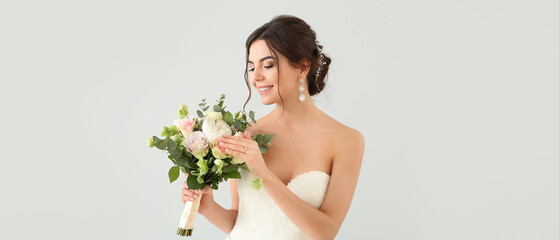 Beautiful young bride with bouquet of flowers on light background - Powered by Adobe