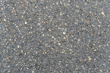 Asphalt texture background top view. Grey small stones on surface of rough road. Bitumen structure wallpaper. Coarse structure of asphalt material.