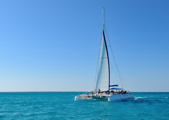 Catamaran with tourists on open sea, blue ocean and blue sky, copy space