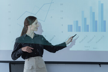 Woman standing at the front projector presenting her idea to colleagues in meeting room ....