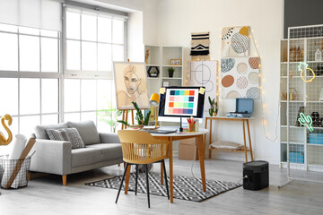 Interior of office with graphic designer's workplace and sofa
