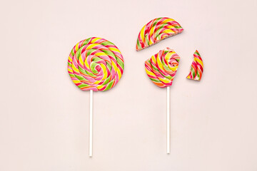 Whole and crushed colorful lollipops on pink background