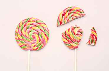 Whole and crushed colorful lollipops on pink background