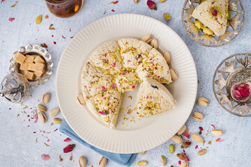 Plate of tasty Tahini halva with pistachios on light background