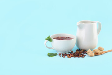 Glass of fruit tea, pitcher and snacks on blue background