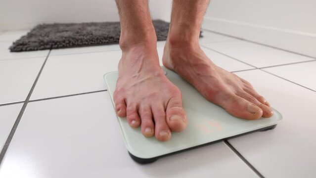 Male feel stepping onto a bathroom scale.