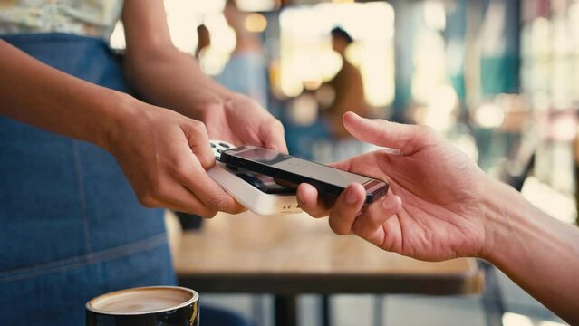 Close up of man in coffee shop paying bill with contactless mobile phone payment - shot in slow motion