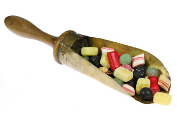 classic Dutch candies in a vintage brass weighing scoop isolated on white background