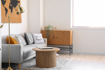 Obraz premium Interior of stylish living room with cozy sofa and modern laptop on coffee table