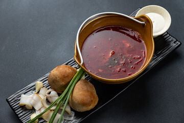 A bowl of soup with two pieces of bread on a wooden board.