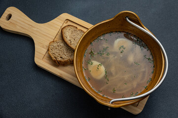 A bowl of soup with two pieces of bread on a wooden board.