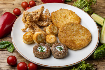 A plate of fried meats with a fried chicken and fried potato.