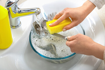 Woman washing knife with sponge in sink, closeup