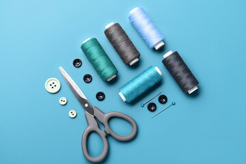 Composition with thread spools, buttons, scissors and ball pins on color background