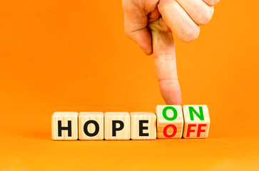 Hope on or off symbol. Businessman turns wooden cubes and changes word Hope off to Hope on. Beautiful orange table orange background. Business and hope on or off concept. Copy space.