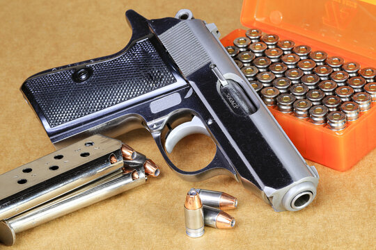 The compact Semi automatic pistol, stainless steel PPKs pistol with spare magazines right side view, Ready for use, lying isolated on white background.