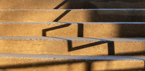 Stark shadows of railings falling across concrete steps at dusk, nobody