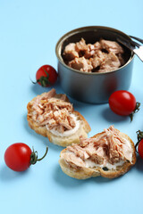 Delicious tuna bruschettas, tin can and tomatoes on blue background