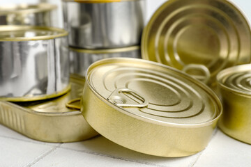 Different tin cans with fish on white tiled table