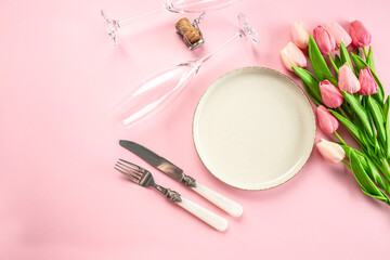 Festive creative table setting plate and tulip bouquet on pink background. Women's Day and Mother's Day