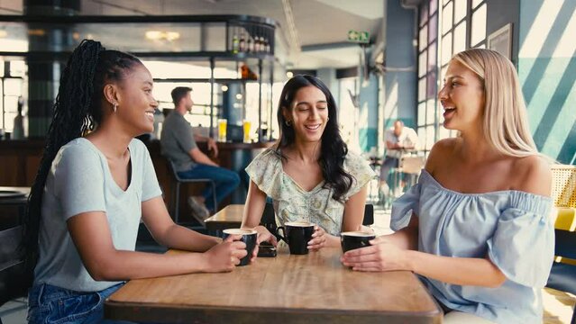 Group of multi-cultural female friends meeting in restaurant or coffee shop catching up and chatting together - shot in slow motion