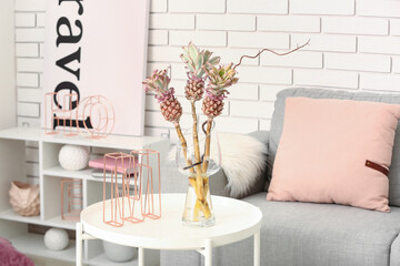 Vase with baby pineapples and decor on table in living room