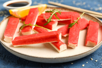 Plate with tasty crab sticks on blue background, closeup © Pixel-Shot