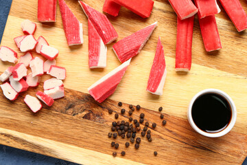 Wooden board with tasty crab sticks and sauce on table, closeup © Pixel-Shot