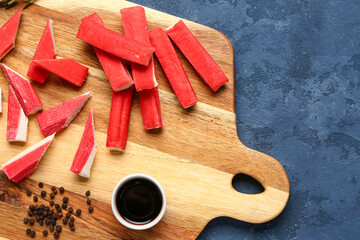 Wooden board with tasty crab sticks and sauce on blue background, closeup © Pixel-Shot